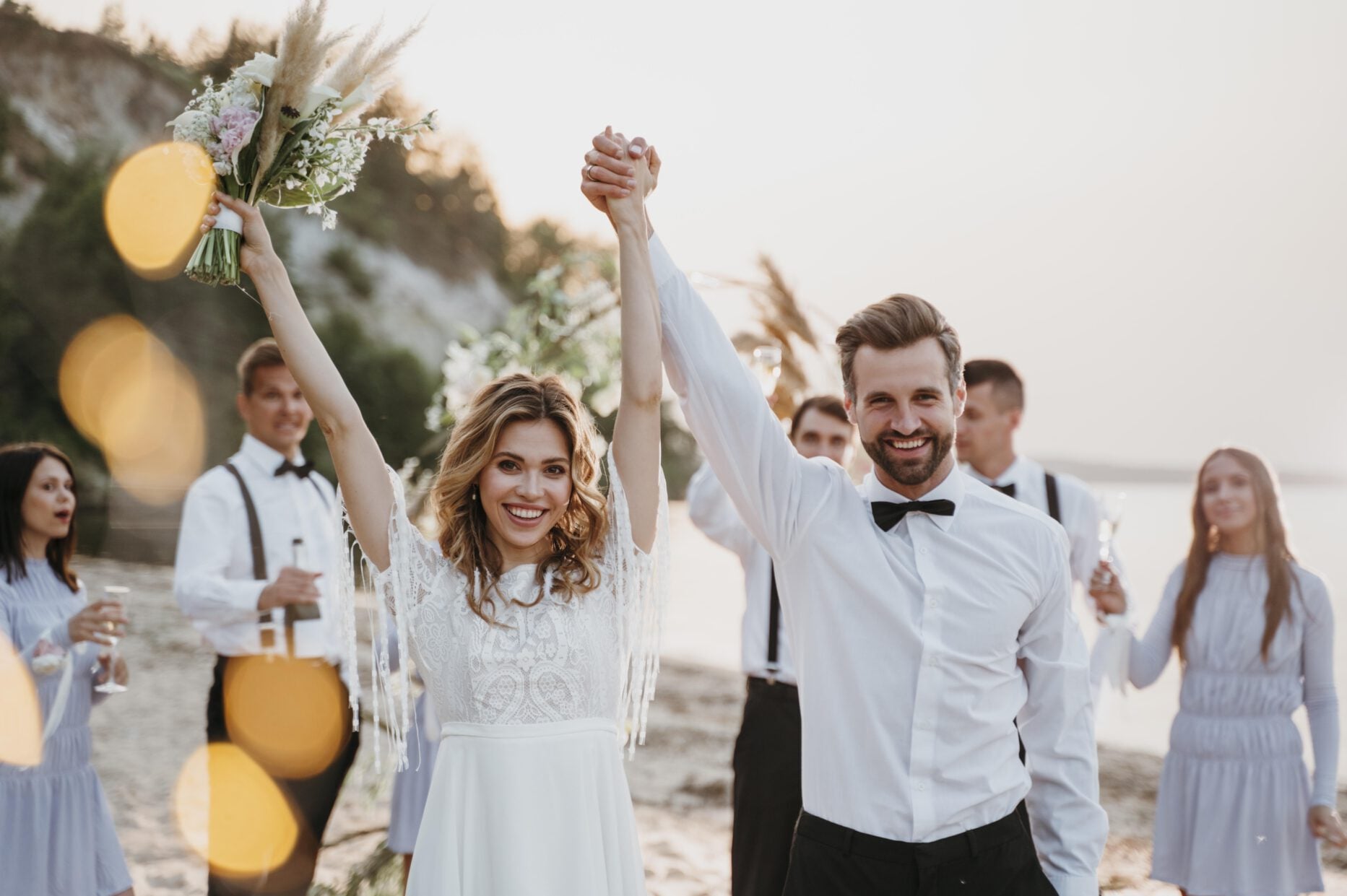 Brautpaar feiert seine Hochzeit mit Gästen am Strand