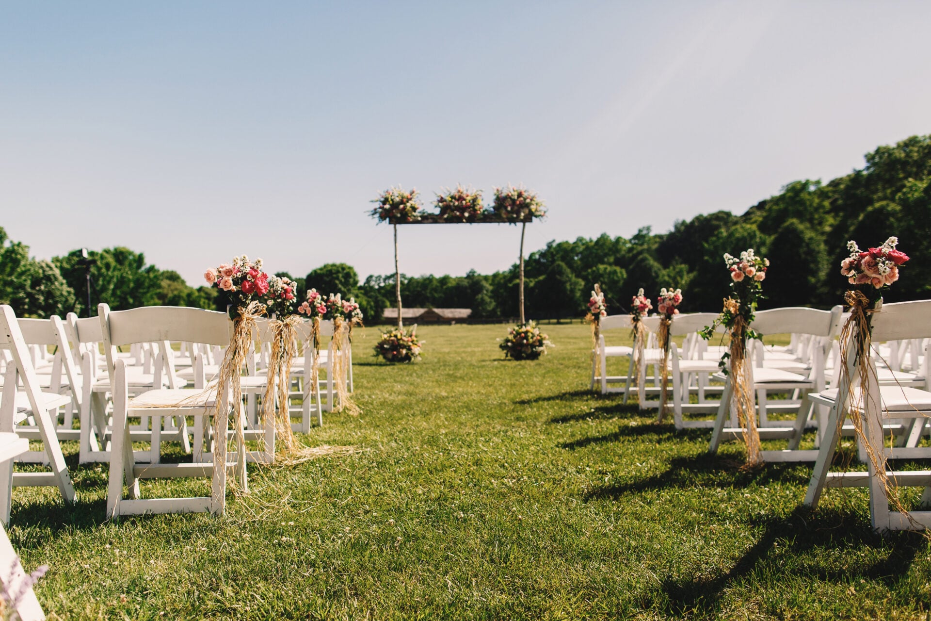 Hochzeitsaltar aus Holzstäben und Blumensträußen im Freien
