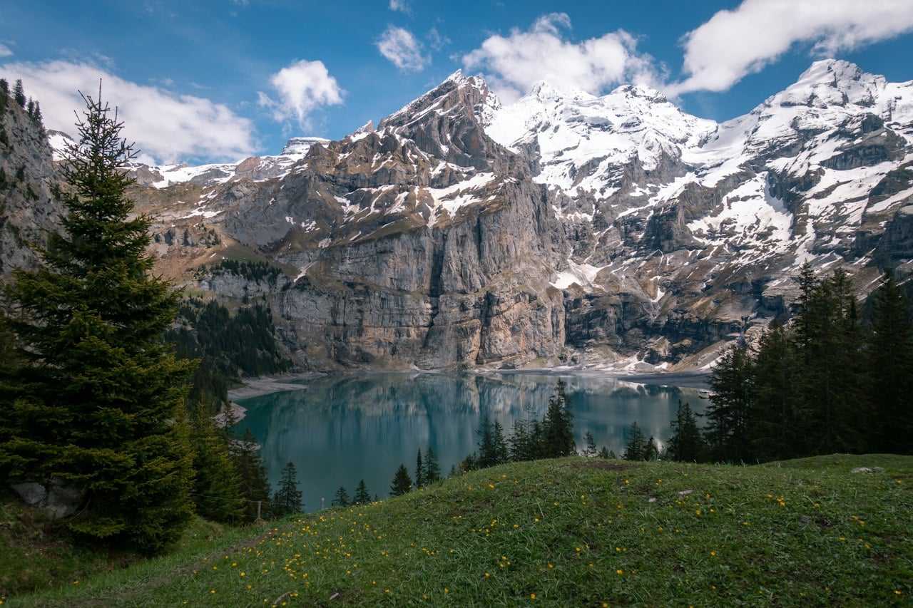 Emerald mountain lake in front of snow-capped Alpine peaks