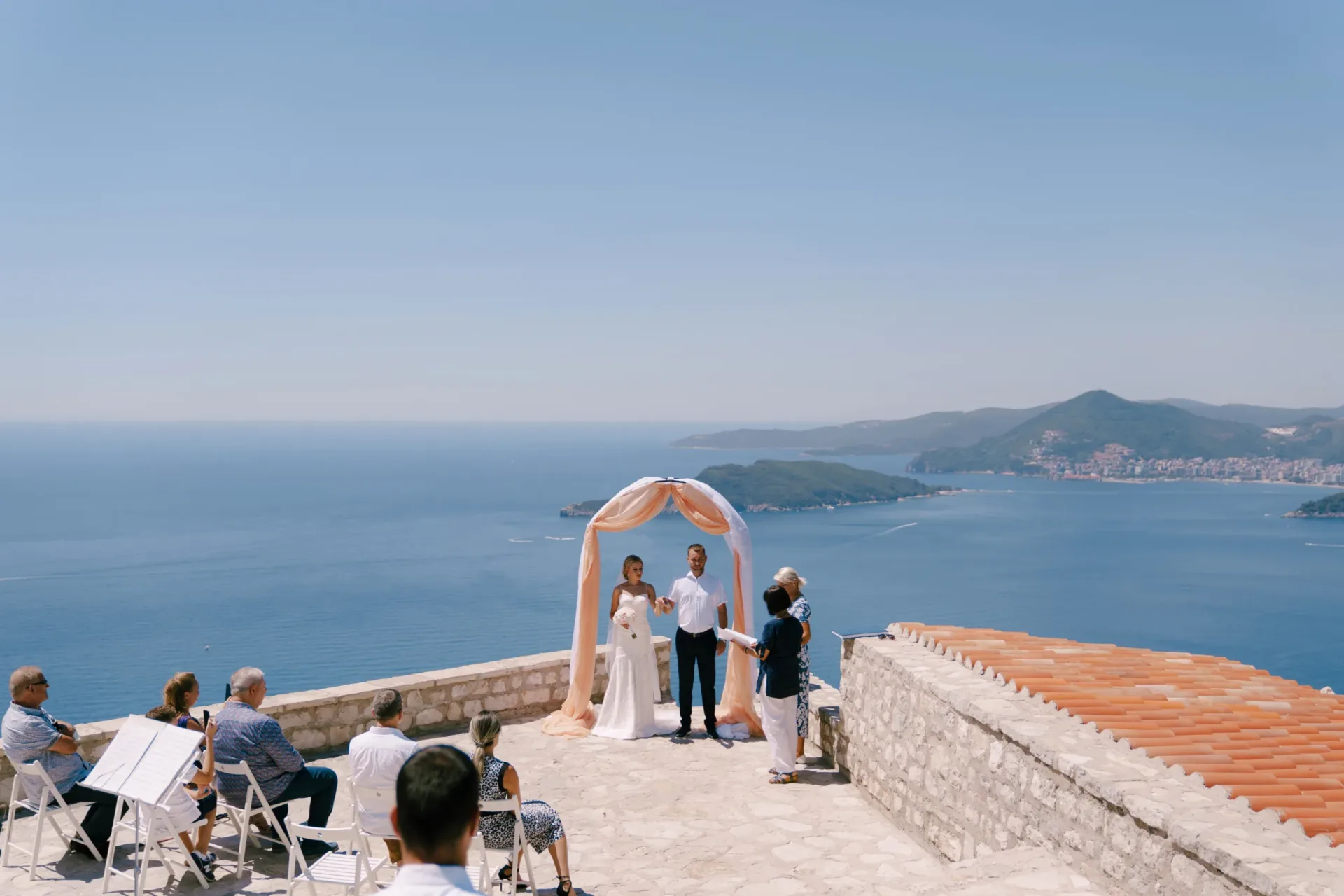 Standesbeamte halten eine Hochzeitszeremonie auf einer gepflasterten Fläche am Meer auf Zypern