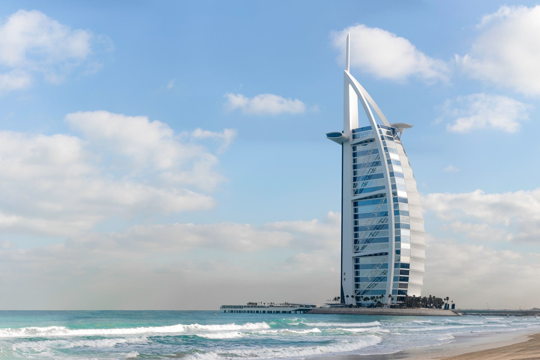 Das Hotel Burj Al Arab am Strand von Dubai vor türkisfarbenem Meer