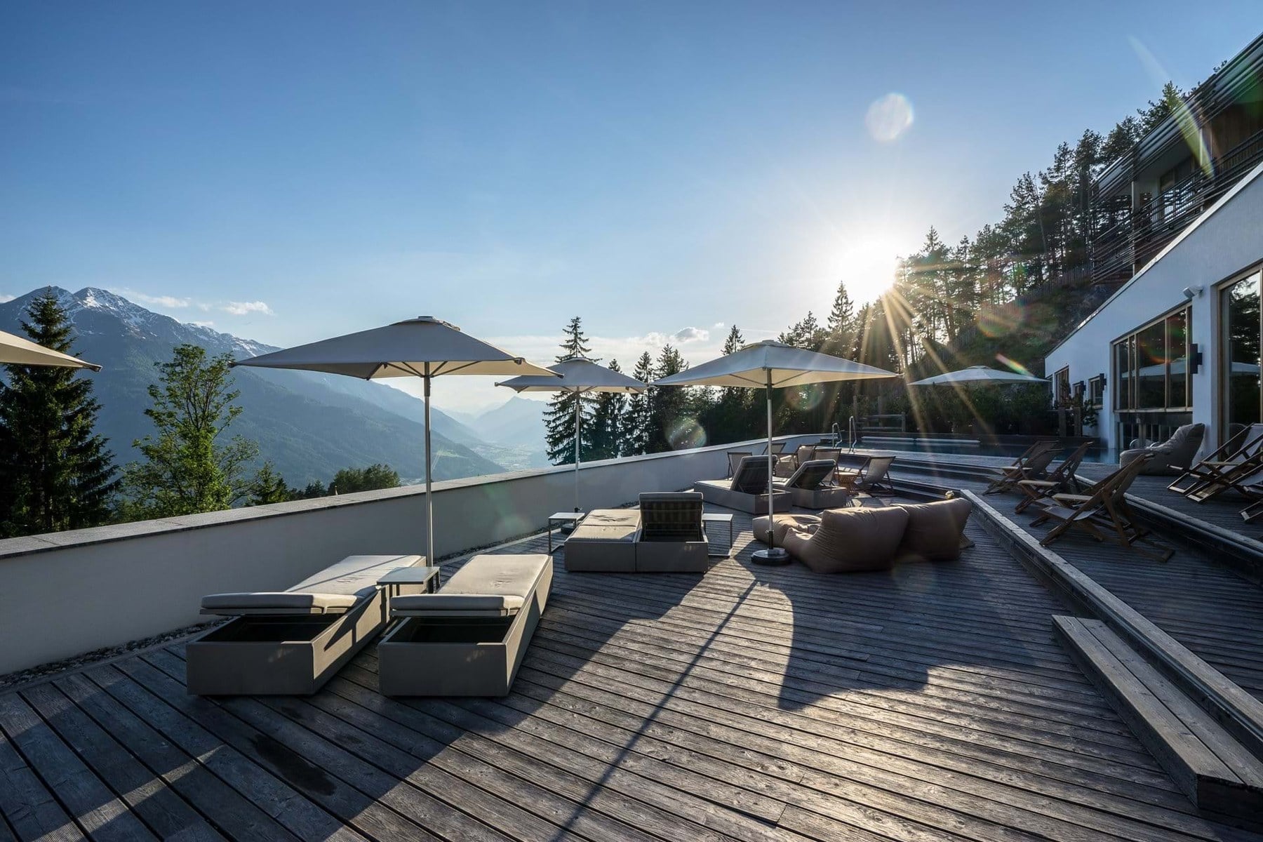 Terrasse eines Berghotels mit Blick über ein Alpental im Abendlicht