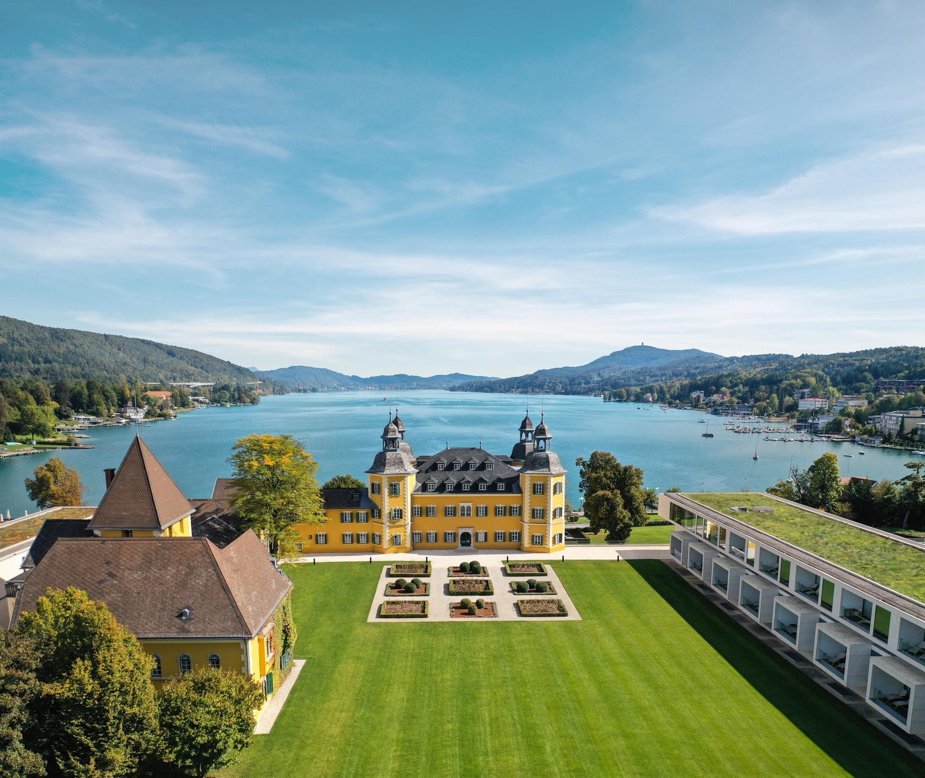 Historisches gelbes Schloss am Ufer des Wörthersees aus der Vogelperspektive