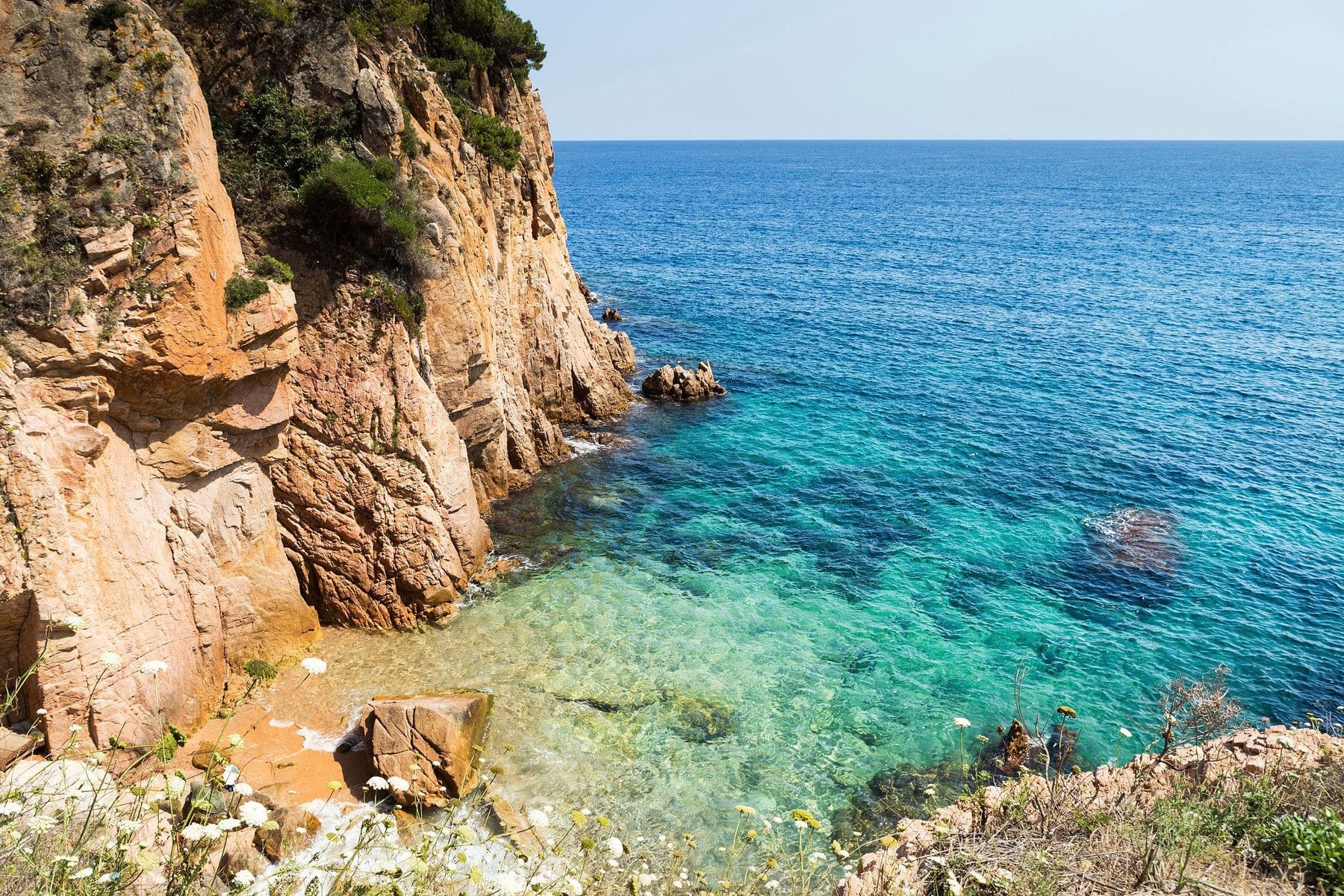 Felsige Steilküste mit türkisfarbener Bucht an der Costa Brava