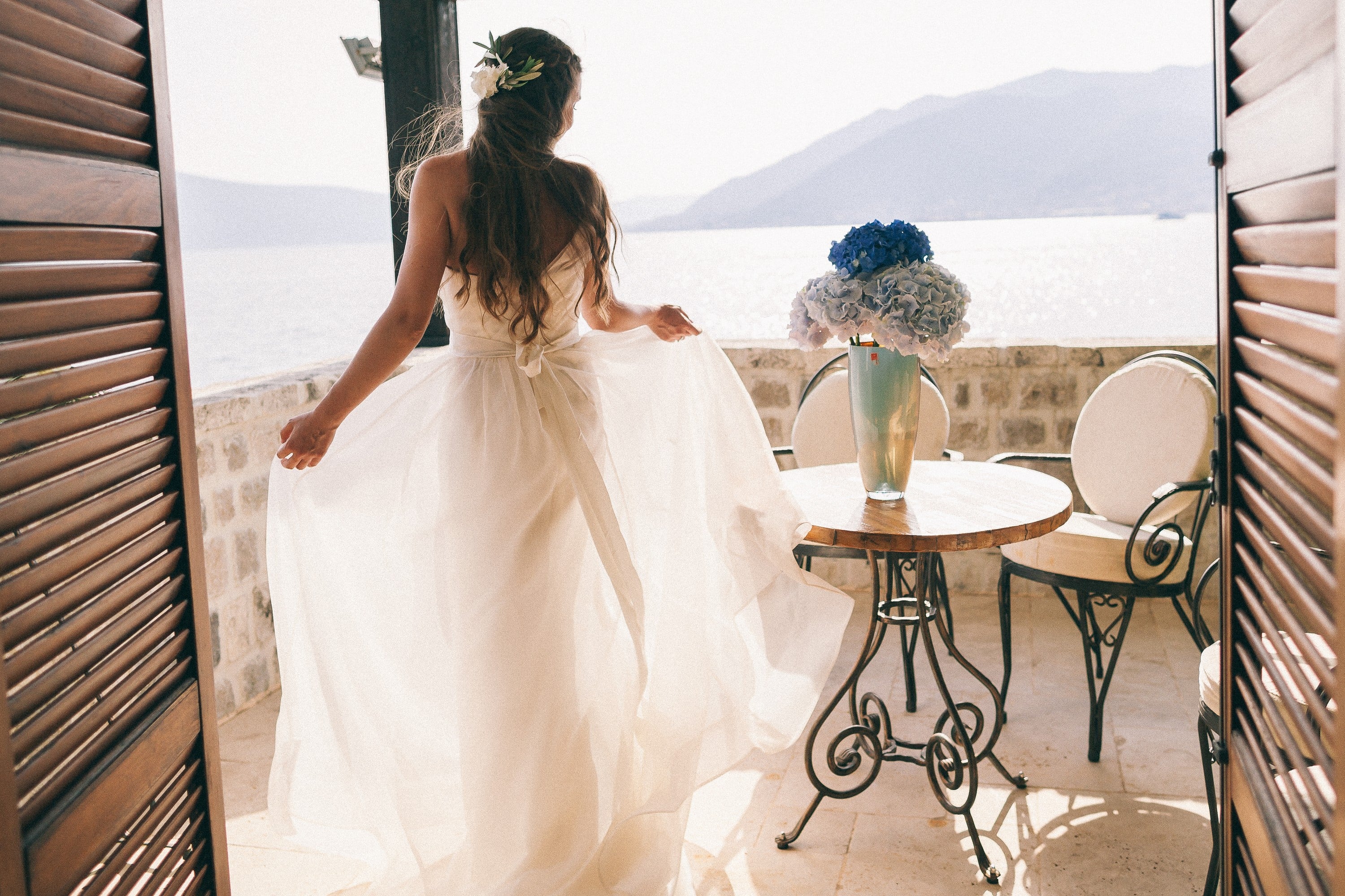 Braut mit wehendem Kleid auf einer Terrasse mit Blick aufs Meer