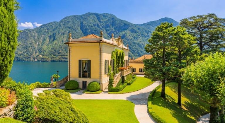 Historische Villa am Ufer des Comer Sees vor bewaldeten Bergen