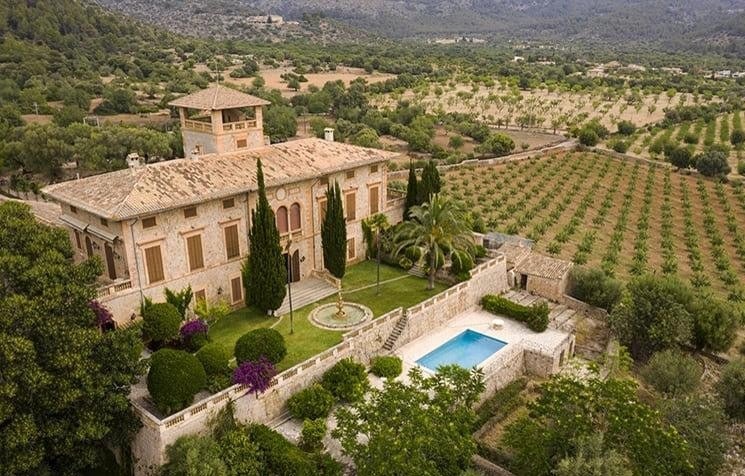 Luftaufnahme einer herrschaftlichen Natursteinfinca mit Pool, Zypressen und Weinbergen auf Mallorca